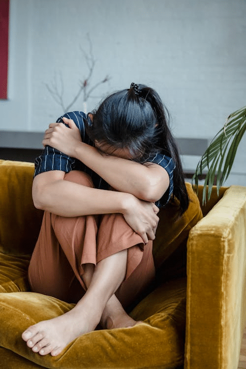 woman sitting alone, crying with hand over face, expressing deep grief and emotional distress