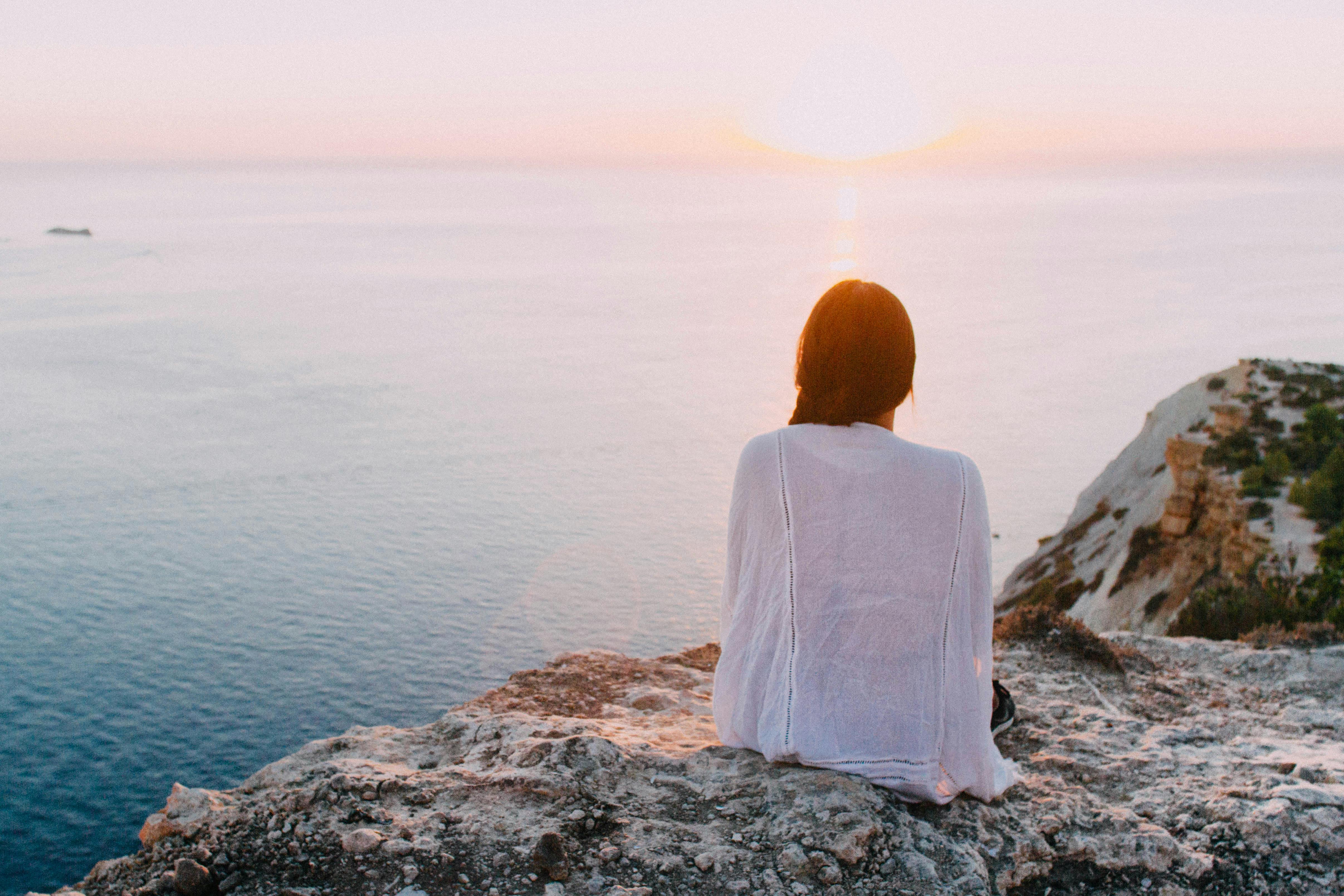 Woman sitting alone by the water, reflecting on managing mental health and seeking balance in life.