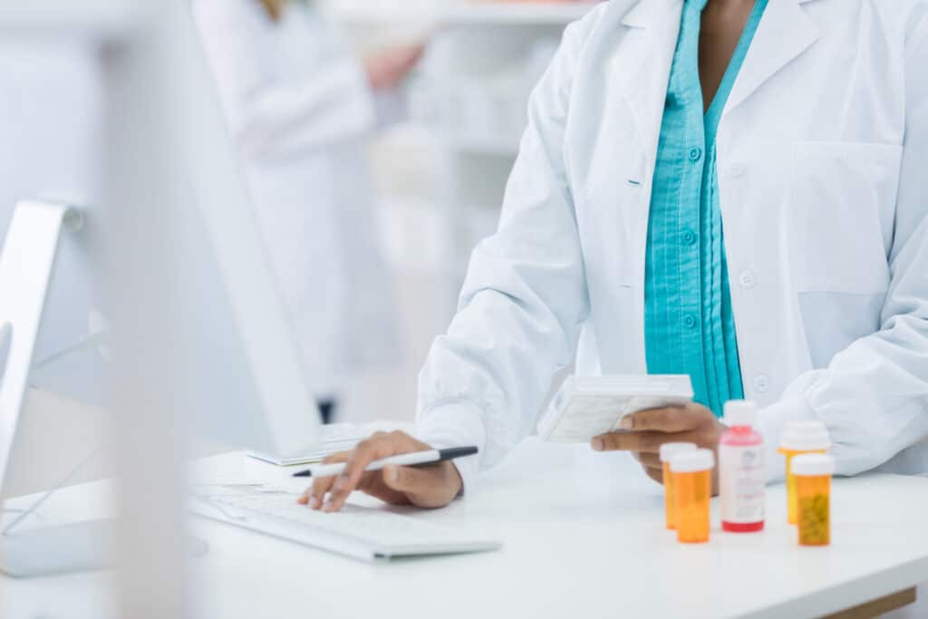 Pharmacy checking computer while filling prescription for customer 1768249357 a45b9777f0e649308d129ca960c7efc2 1