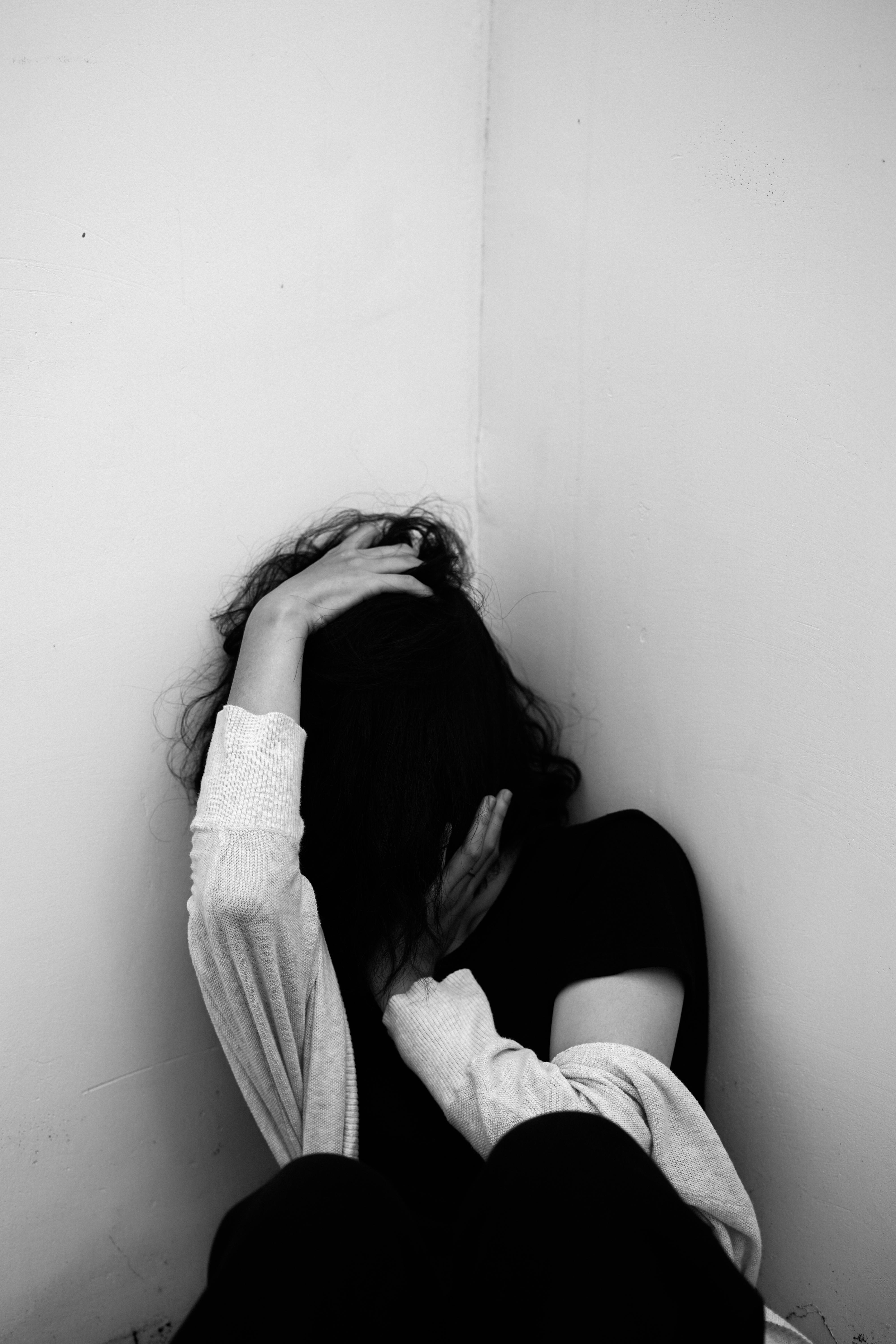Woman sitting in a corner with hands on head, showing emotional distress, possibly linked to inflammation